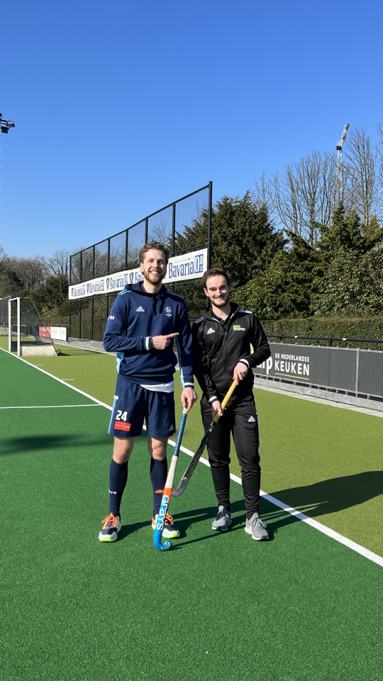 Hockeyer Jasper van der Looy staat samen met sportfysiotherapeut Mathias Thoelen op het hockeyveld. Topsporter Jasper van der Looy revalideert na een dubbele achillespeesblessure bij Anna TopSupport en staat weer op het hockeyveld.