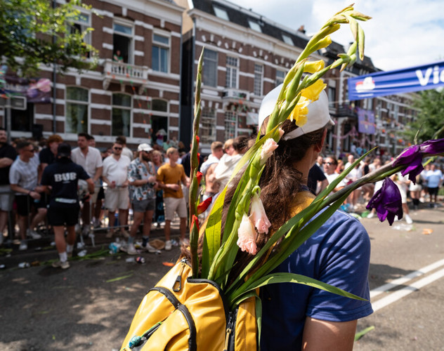 Vrouw wandelt richting de finish van de Nijmeegse Vierdaagse. Ze draagt een rugzak met daarin bloemen.