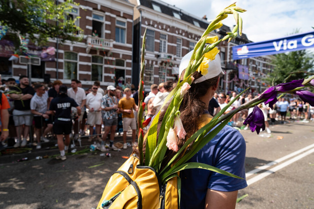 Vrouw wandelt richting de finish van de Nijmeegse Vierdaagse. Ze draagt een rugzak met daarin bloemen.